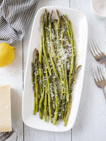 A platter of air fried asparagus topped with parmesan cheese and lemon zest.