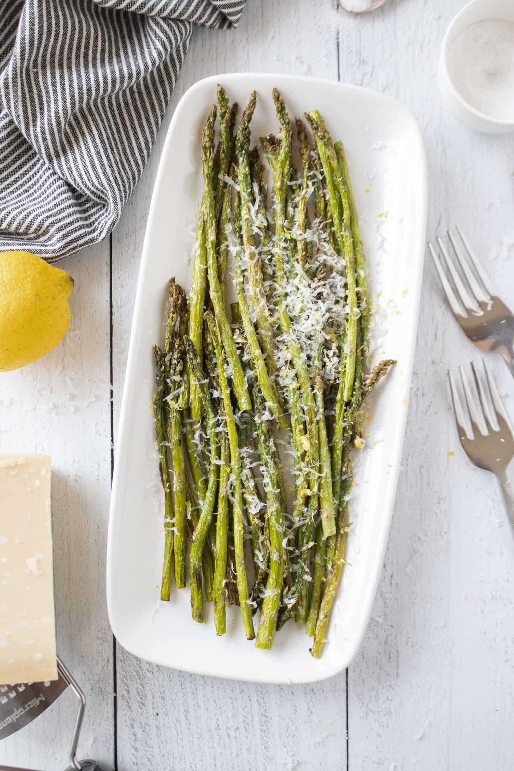 A platter of air fried asparagus topped with parmesan cheese and lemon zest.