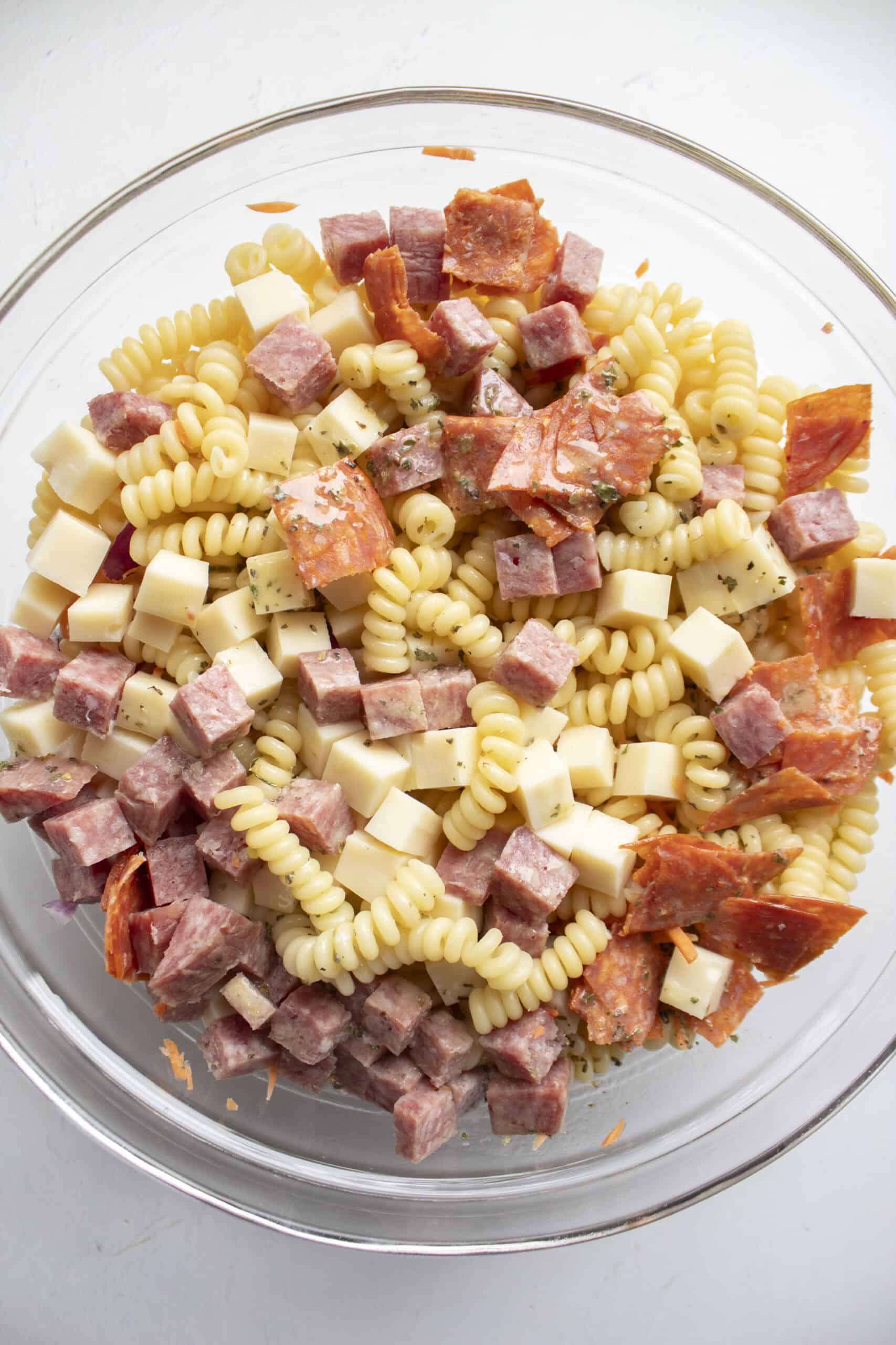 Pasta with shredded carrots, red onion, pepperoncini topped with cubed deli meats, cubed provolone cheese, and an Italian dressing.