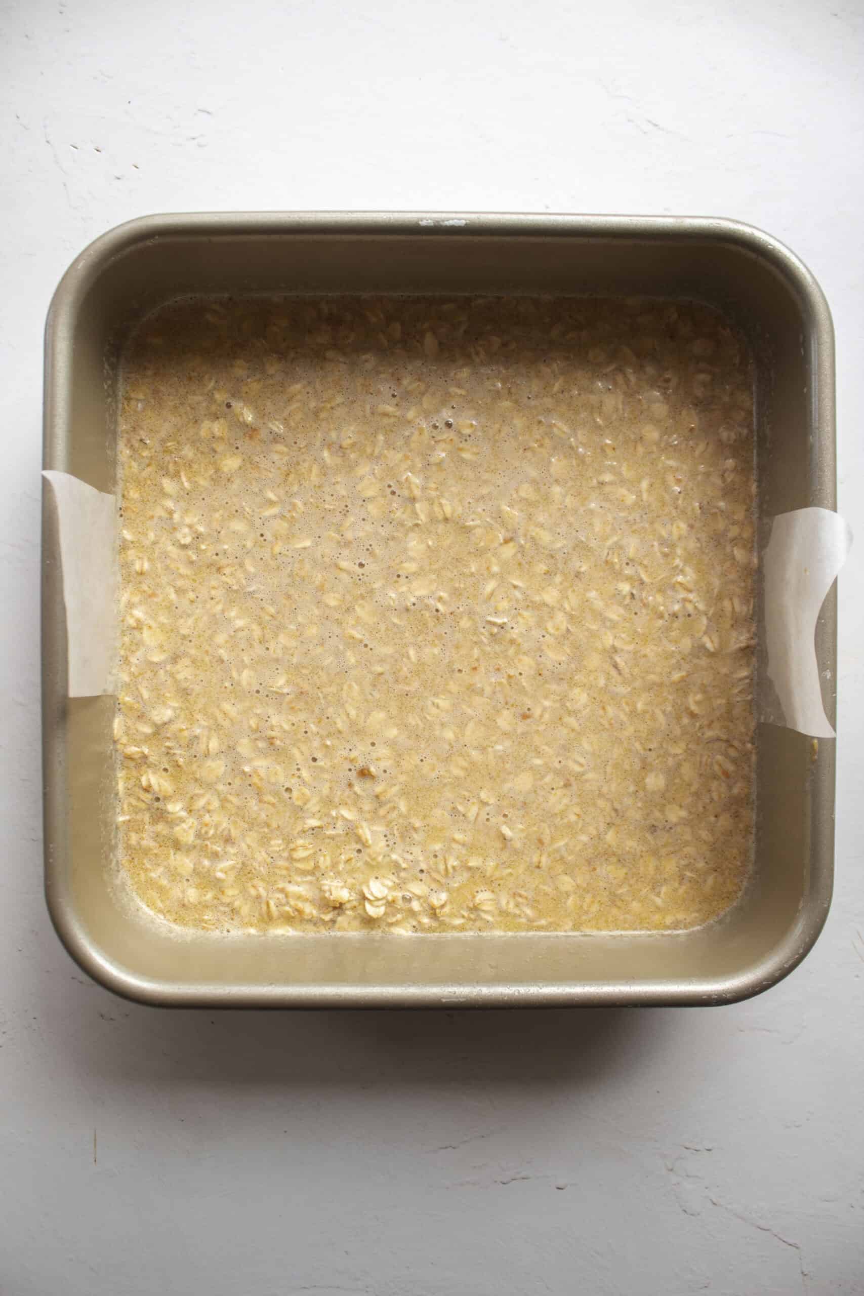 Peanut butter oatmeal bake before baking in a pan lined with parchment paper.
