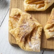 Close up of a pear and brown butter puff pastry tart on a wooden serving board.