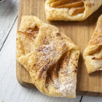Close up of a pear and brown butter puff pastry tart on a wooden serving board.
