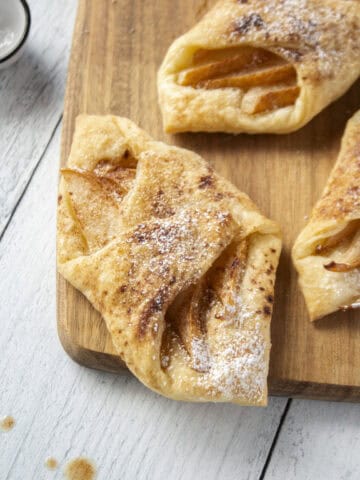 Close up of a pear and brown butter puff pastry tart on a wooden serving board.