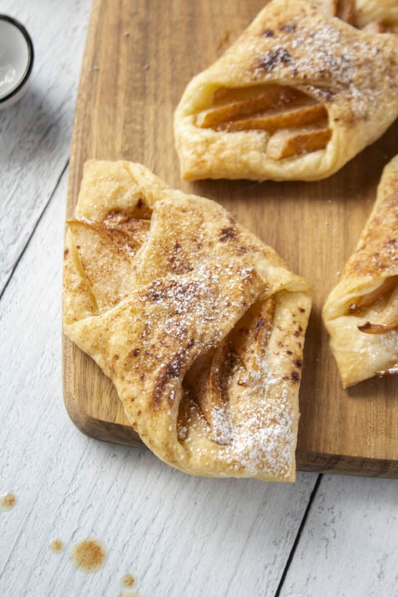 Close up of a pear and brown butter puff pastry tart on a wooden serving board.
