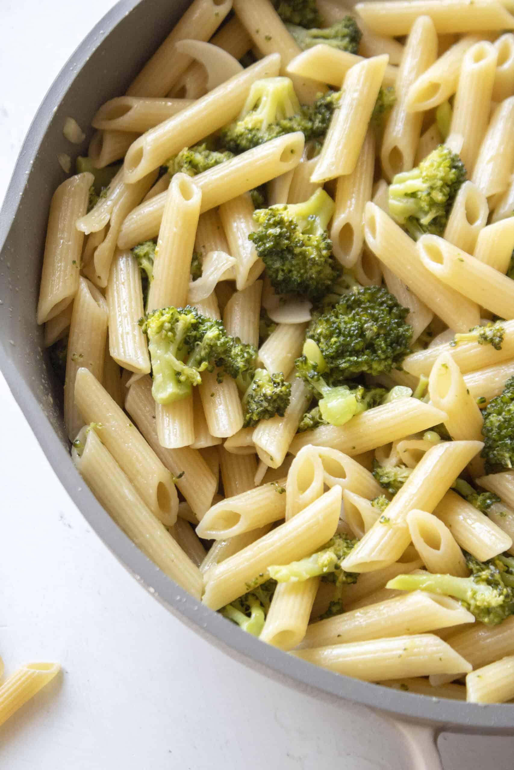 Close up of penne pasta with garlic broccoli in a frying pan.
