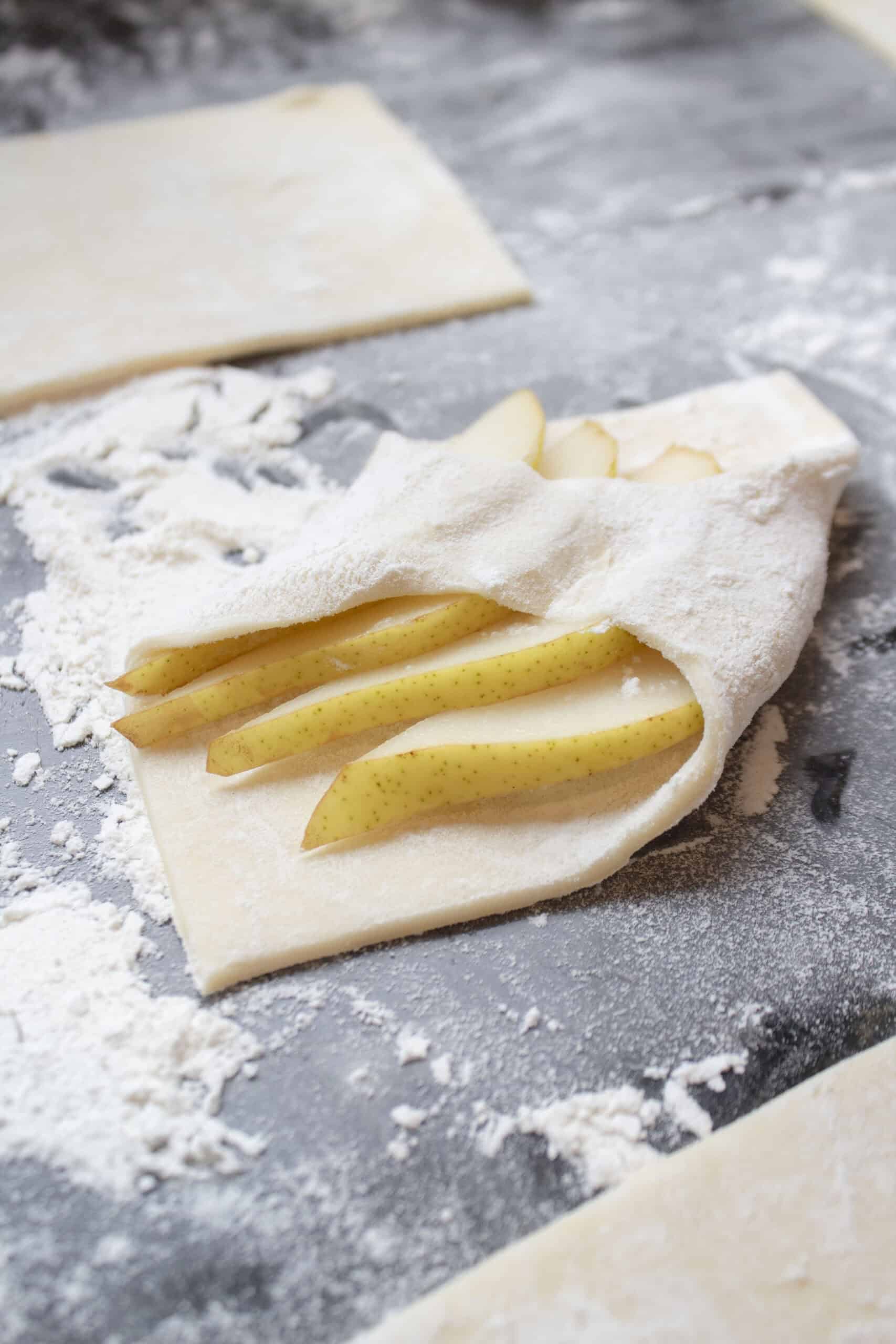 Puff pastry squares with several slices of pear, then folded diagonally.