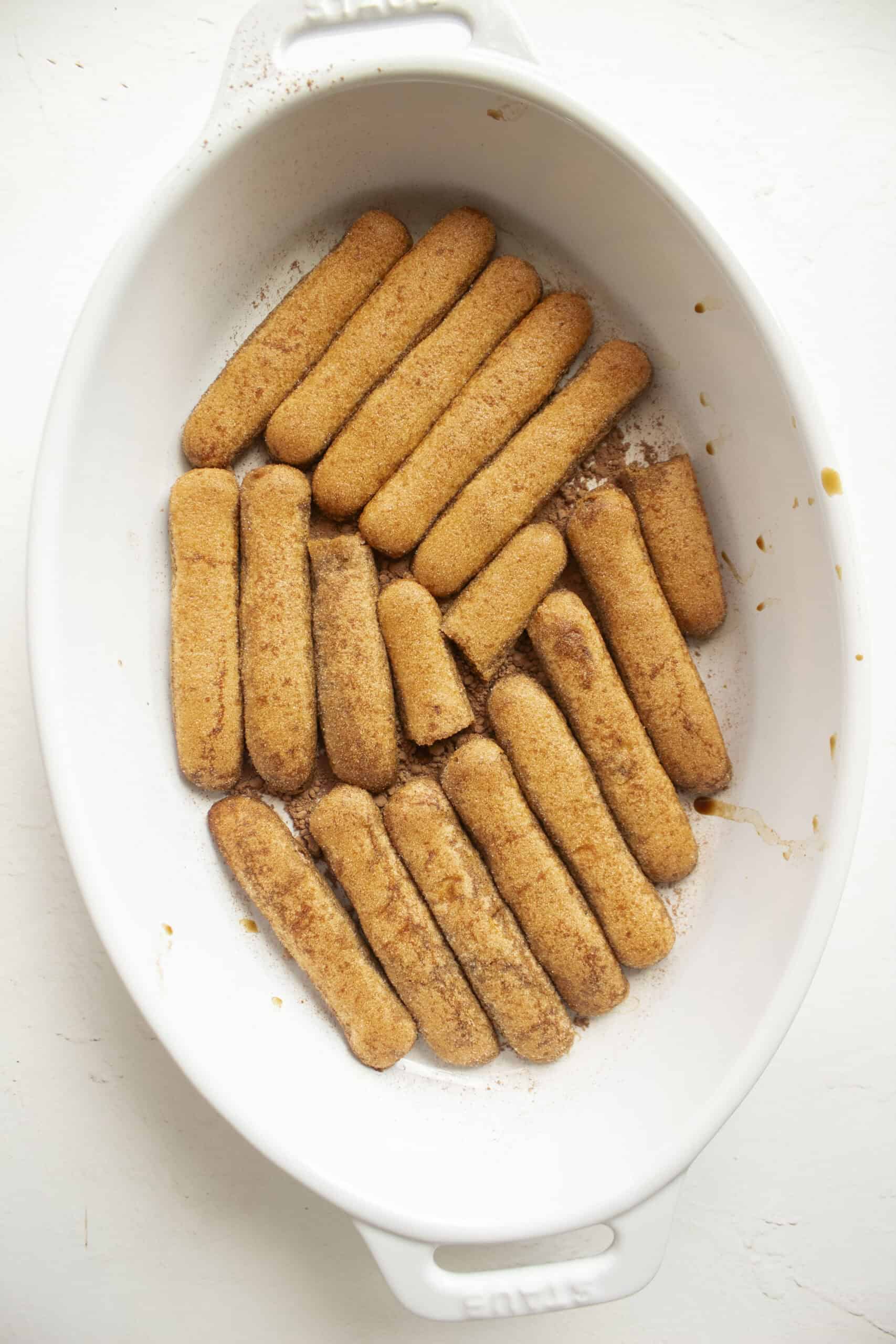 Soaked ladyfingers in espresso in a ceramic dish.
