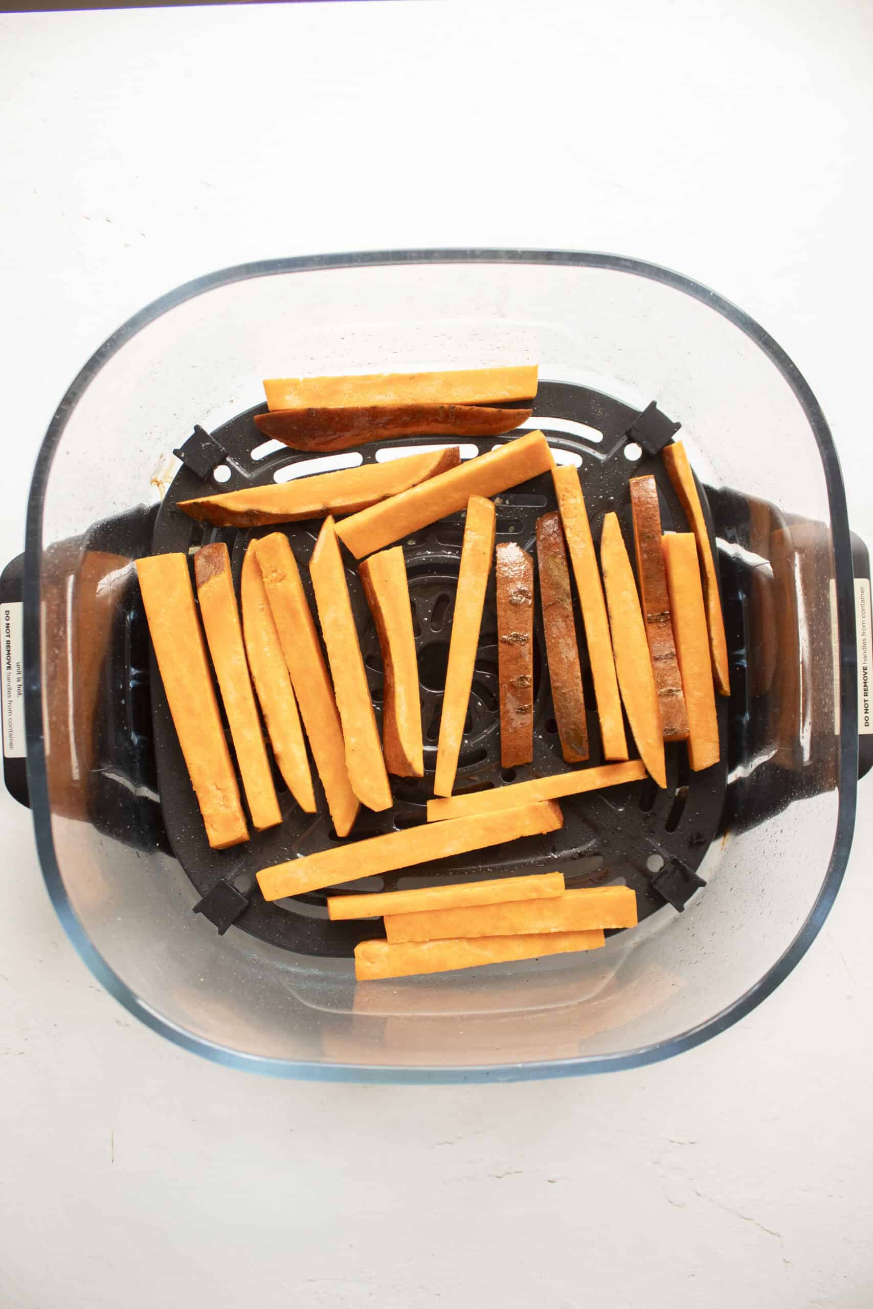 Sweet potato fries tossed in olive oil and added to the air fryer in a single layer.