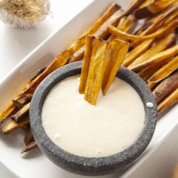 Three sweet potato fries dipped into the garlic aioli surrounded by more sweet potato fries.