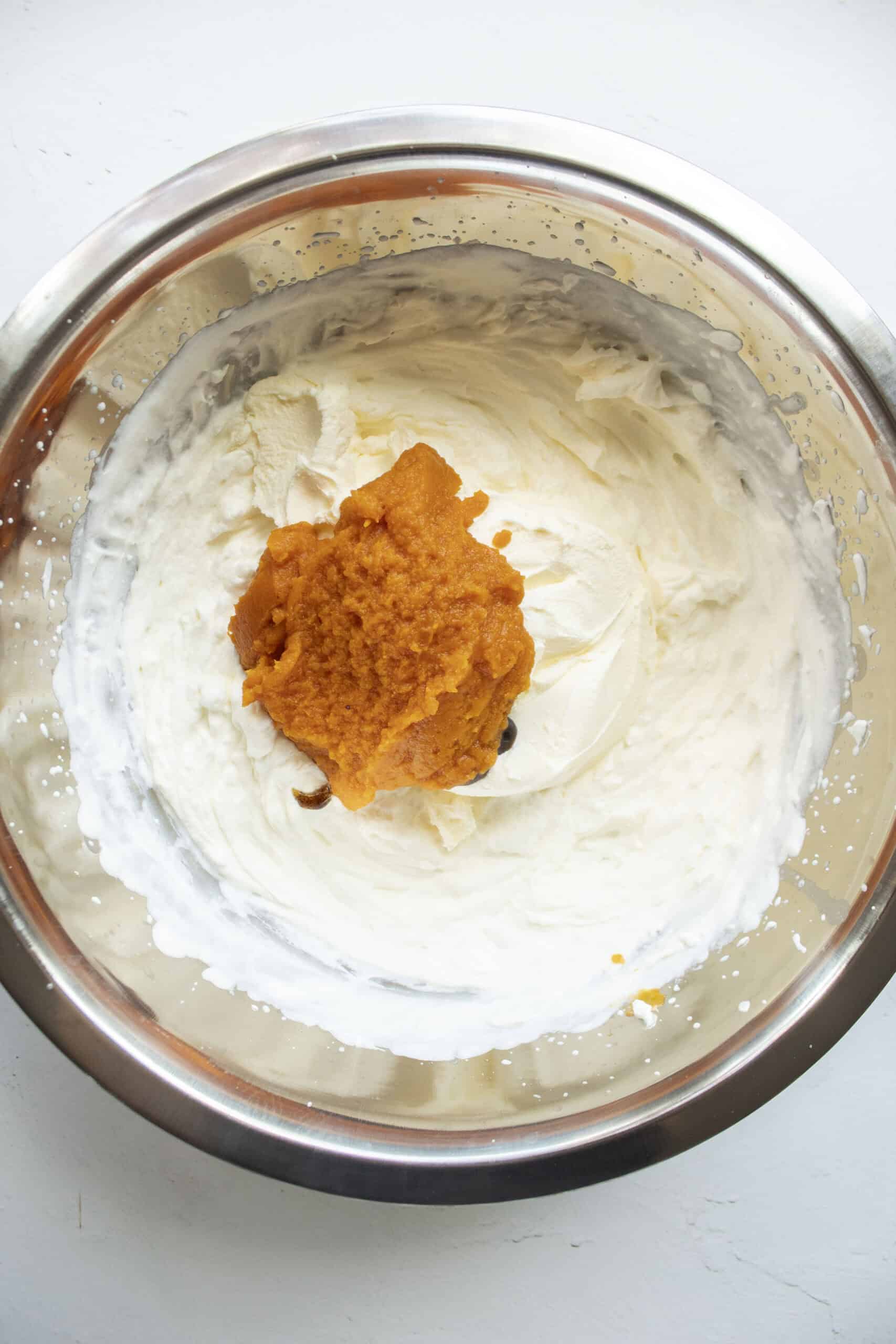 Whisked heavy cream with sugar, pumpkin puree, vanilla paste, and mascarpone cheese in a large mixing bowl.