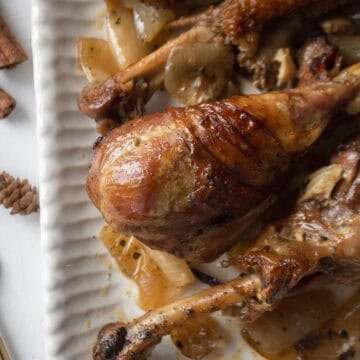Close up of apple cider braised turkey drumsticks in the dutch oven on a serving platter.