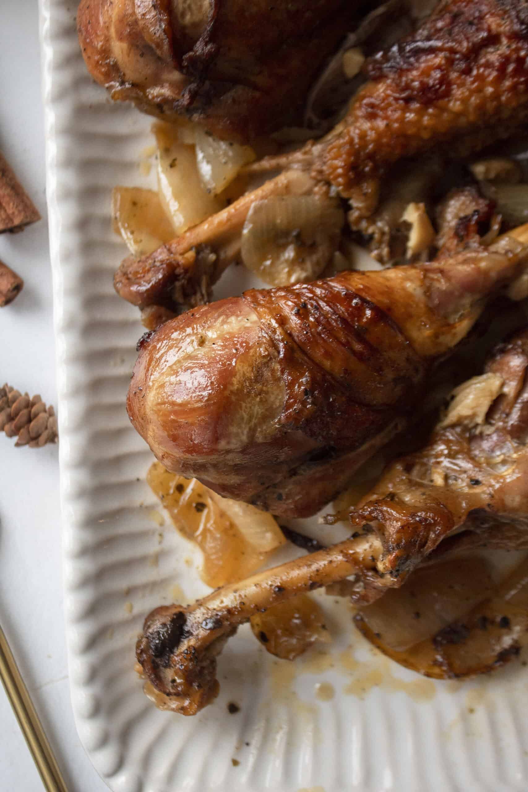 Close up of apple cider braised turkey drumsticks in the dutch oven on a serving platter.