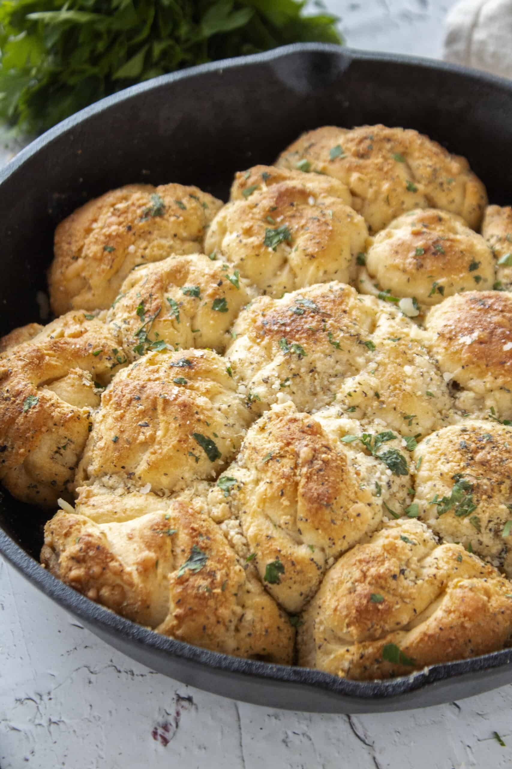 Close up of parmesan garlic crescent roll bread in a cast iron skillet.