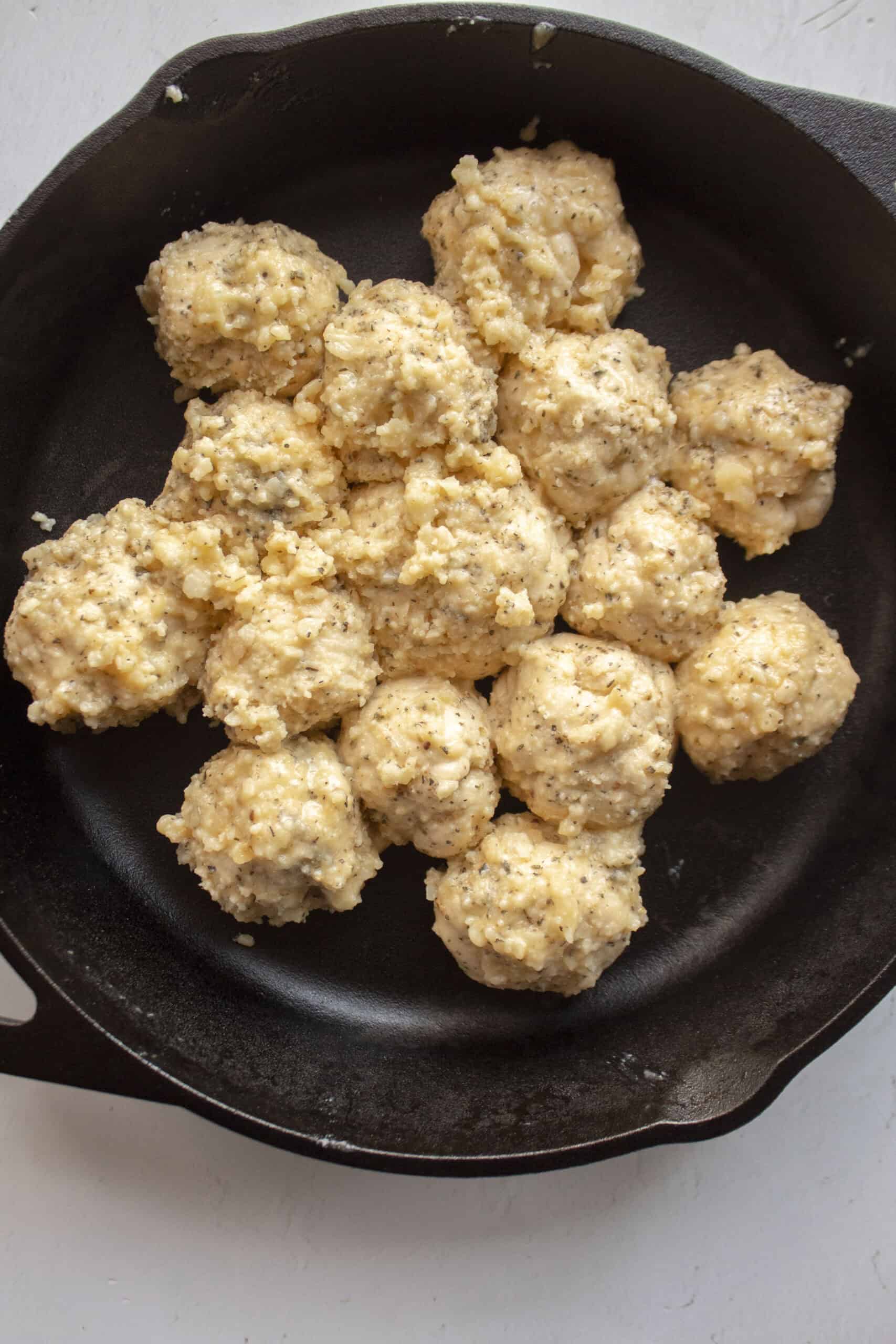 Crescent roll balls tossed in melted butter, parmesan cheese, Italian seasonings, and salt then placed in a greased cast iron skillet.