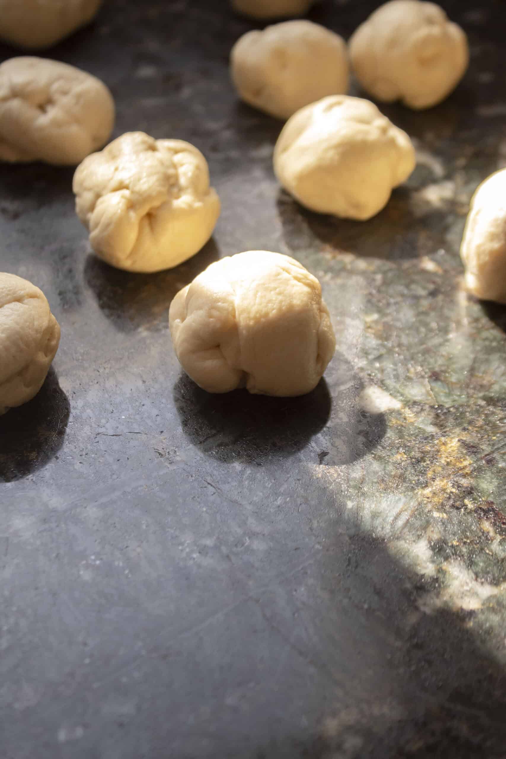 Crescent roll dough cut into strips, then rolled into smaller dough balls on a countertop.