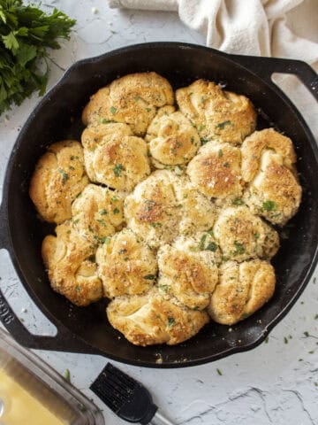 Garlic parmesan crescent roll pull apart rolls baked in a cast iron skillet topped with parsley.