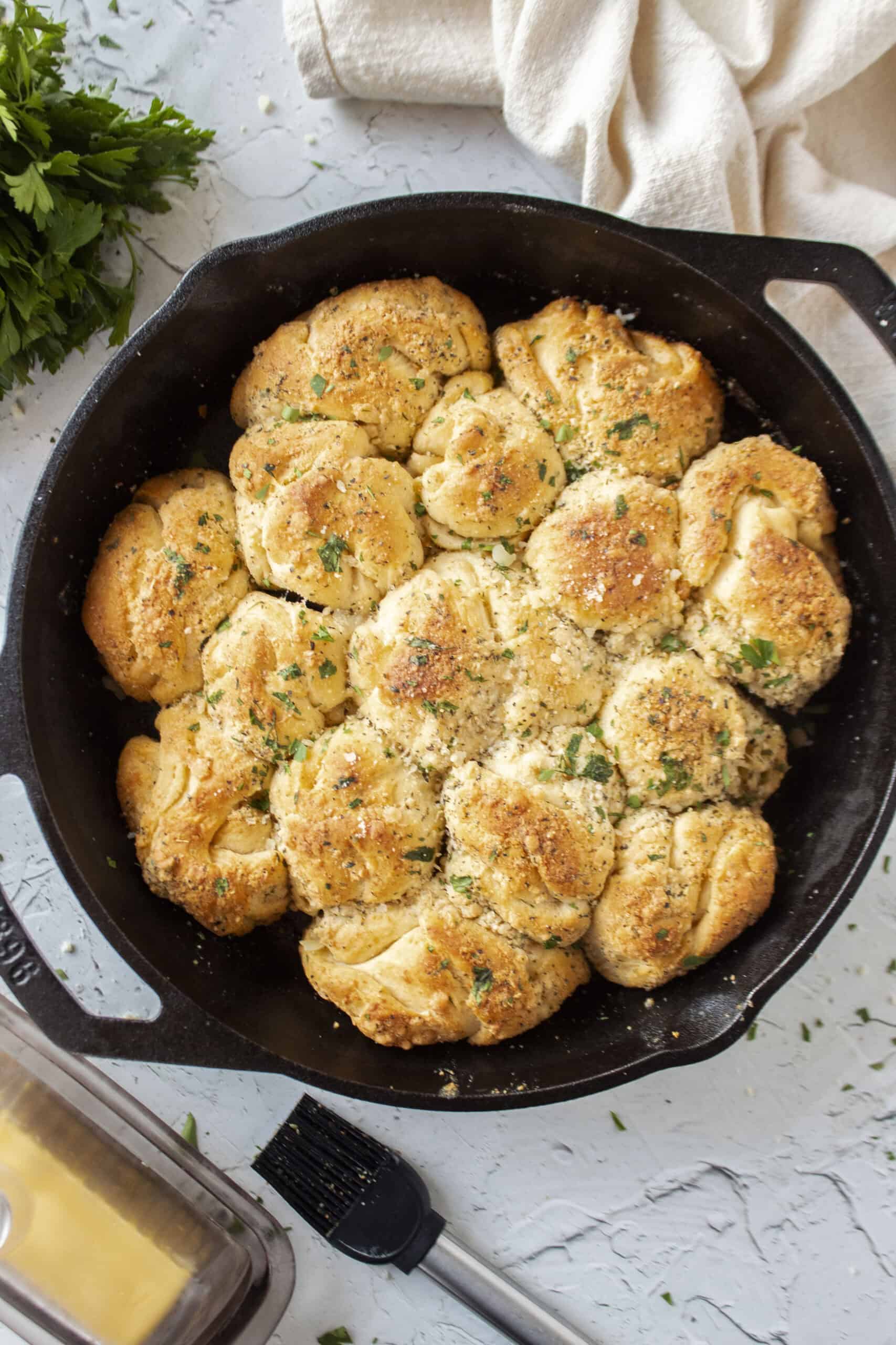Garlic parmesan crescent roll pull apart rolls baked in a cast iron skillet topped with parsley.