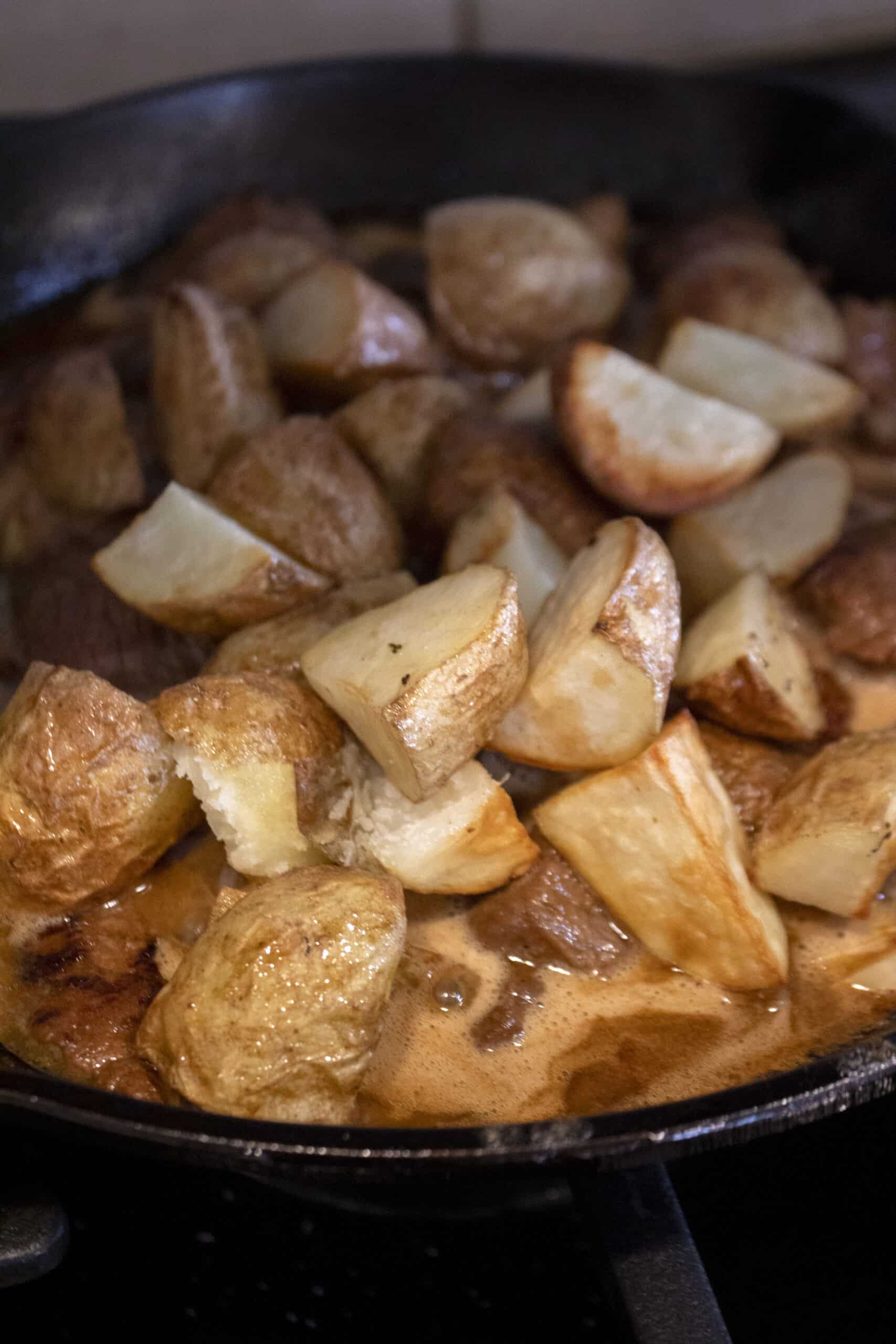 Air fried potatoes tossed into a cast iron pan with seared steak tips in garlic butter sauce.