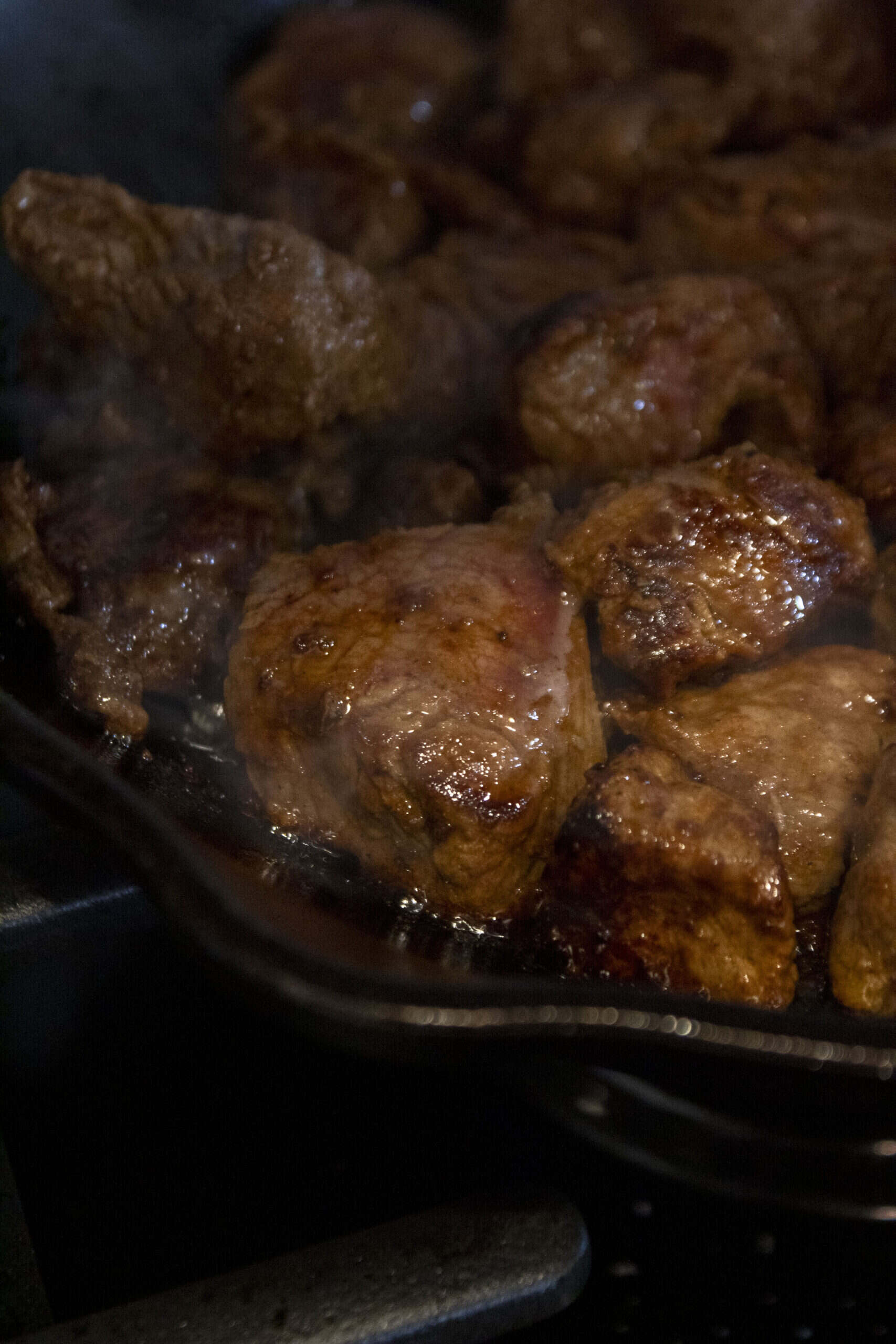Close up of steak tips in a cast iron skillet on the stove.