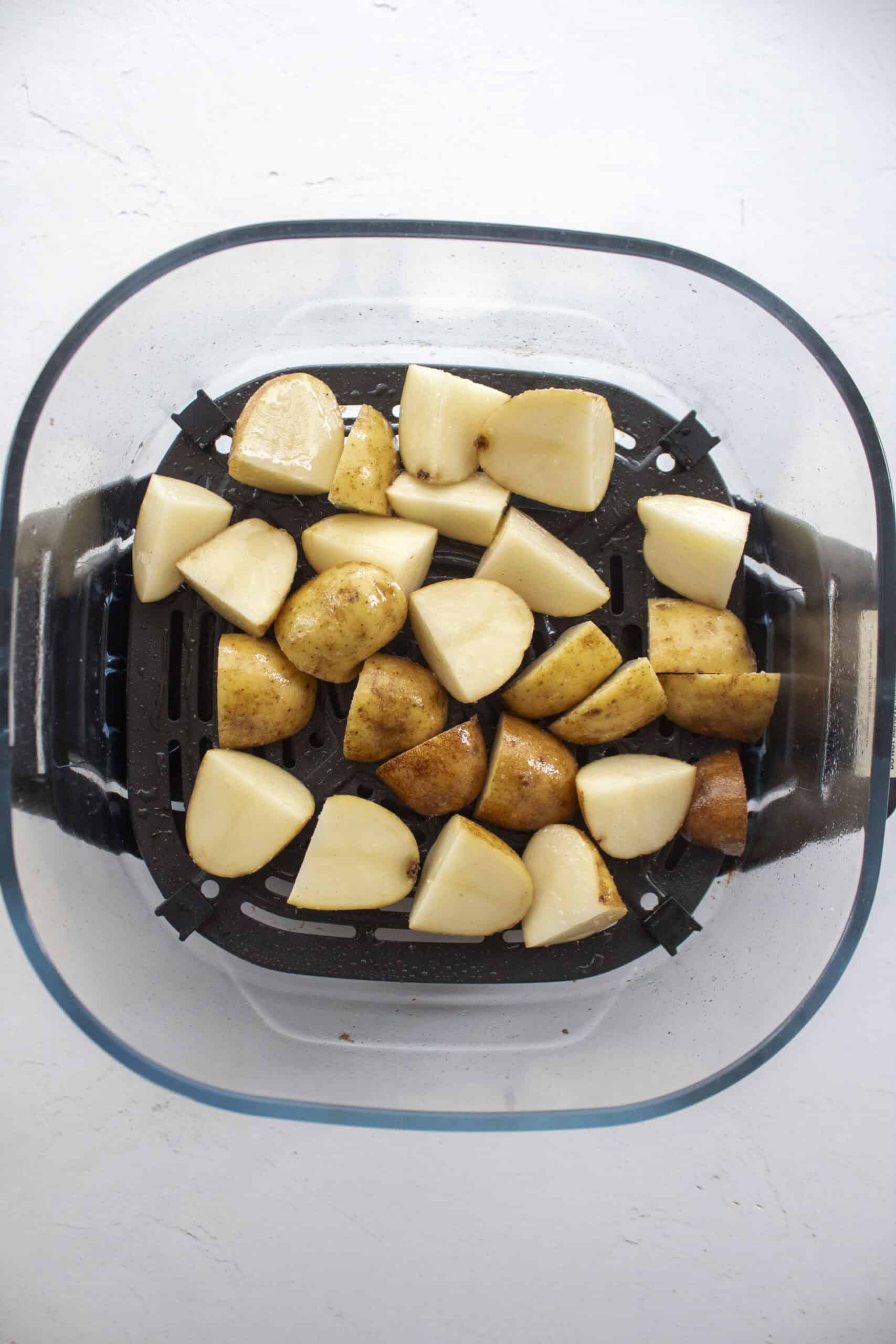 Diced russet potatoes tossed together with olive oil and salt in an air fryer.
